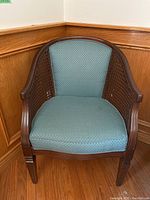 Front view of the side chair showing blue upholstered seat and back, wood frame and cane sides.