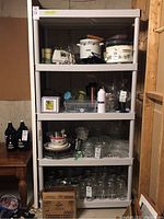 Full view of resin utility shelving unit five-tiered with various household items on shelves (not included in sale). The unit is beige/gray, standard aimed for storage purposes.