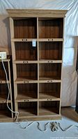 Front view of tall wooden book case showing ten square compartments and metal label holders