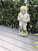Front view of the cement boy statue showing detailed coat and hand placement