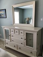 Front view of off-white dresser with attached mirror above