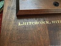 Close-up photo showing L. Hitchcock brand name stamped on the underside of one table.