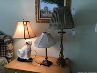 All four lamps displayed on wooden surface in front of wall art.