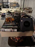 Overview of lot showing console, controllers and game cases in cardboard box