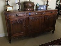 Front view of sideboard showing three drawers and carved doors