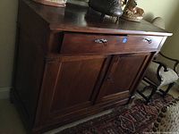 Front view of vintage wooden sideboard showing single drawer with metal handle above two-door cabinet
