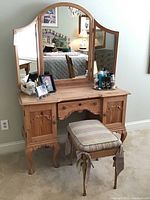 Front view of the wooden vanity with tri-fold mirror and matching stool with plaid cushion