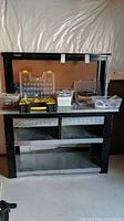Full view of black metal Husky workbench with pegboard back holding several tool boxes and assorted items on top and below.