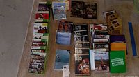Top view of collection of Xbox 360 games, DVDs, CDs, and Northern Exposure item on carpet floor.