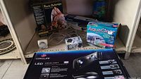Photo showing Coralife LED Aqualight box, AquaClear filter box, various cords, and ExoTerra Rock Outcrops hiding cave box displayed on shelf.