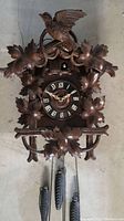 Full view of wooden cuckoo clock with carved bird and leaves, bird carving is loose.