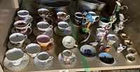 Wide view of entire lot arranged on shelf including cups, saucers, mugs, cream and sugar set, salt and pepper shakers, and small dishes