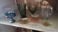 Front view of entire lot with green vases, clear cake server, pitcher with gold trim, and carnival glass dishes