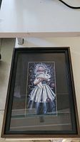 Framed print showing full artwork and frame on a white floor, displaying the entire piece, black frame, and matting.