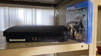 Side view of PS3 console showing USB ports and part of console shape with 2 PS4 game cases, Titanfall 2 visibly shown.