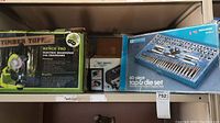 Shelf showing boxed Timber Tuff Bench Pro Chainsaw Sharpener, Wen Wet Wheel Sharpener, and Mastercraft 60-piece Tap and Die Set