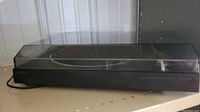 Sony PS-LX100 automatic stereo turntable system with transparent dust cover closed, showing the front and side profile.