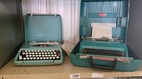 Two portable manual typewriters side by side in teal cases