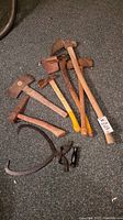 Overview of all items: two axes, two ice picks, a pick-like tool, and ice block tongs on carpeted floor