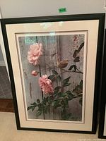 Full view of framed art print depicting pink roses with a bird in front of a rustic wooden background.