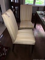 Two Parsons chairs with cream slipcovers and dark wood legs shown from side angles.