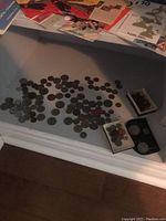 Wide view of all coins spread on white shelf with some coin containers present.