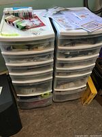 Two tall plastic drawer storage units filled with assorted craft supplies