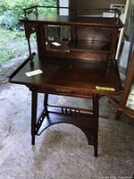 Front and side view of vintage tiered wood desk showing upper and main surfaces, underside drawer, and lower shelf.