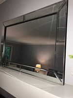Full mirror view showing rectangular shape, beveled mirrored frame with reflective segmented frame segments.