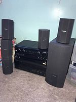 Photo of the full stereo system including two large speakers, an amplifier/receiver, and several satellite speakers.