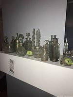 Side view of various vintage apothecary and perfume bottles arranged in a row, showing variety of shapes and sizes.