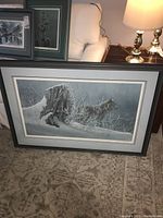 Full view of framed print leaning against couch showing frame style and subject matter