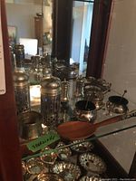 Two pierced silver shakers with cobalt liners, two napkin rings, wooden-handled server, silver dishes and condiment pots on glass shelf