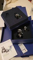 All three crystal panda figurines in foam insert inside branded Swarovski box alongside booklet and tag