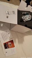 Opened white Swarovski box showing foam insert and paperwork beside crystal elephant