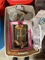 Top view showing three antique lighting pieces including brass wall sconce, glass lamp shade, and cylindrical glass candle holder all contained in a plastic bin.