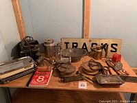 Photo showing the full assortment of antiques including scale, kettles, meat grinder, pallet weights, brass oil can, and the Canadian Price Guide book