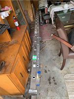 Two long aluminum ladder sections with ladder rung holes and blue feet caps; photo shows the entire length and adjacent furniture and garage environment.