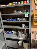 Wide photo showcasing metal shelving unit filled with various containers of nuts, bolts, screws, and small hardware pieces