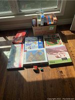 Overview of the puzzles and games arranged on floor in sunlight showing box sets, puzzles, and Rubik's cubes