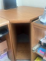 View of the corner wood table's open storage compartment and angled shape to fit into corners.