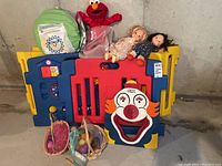 Lot of colorful plastic playpen panels, two Fisher-Price dolls, Easter eggs in baskets, clown target board, Elmo doll, and green infant cabana