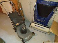 Black & Decker Lawnforce lawn mower beside Lambert Mark 26 sweeper in basement, view showing mower body, handle and sweeper frame with collection bag