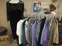 Photo showing black velvet dress with lace top and other clothing hung on a clothes rack, Philips Norelco electric shaver in packaging on shelf above