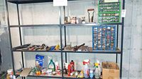 Wide shot of metal shelving unit holding various containers, cleaning supplies, and hand tools. Blue and green plastic organizers with multiple small drawers filled with hardware items are on the shelves.