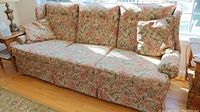 Left-side angle view of floral tapestry wingback sofa showing fabric pattern, cushions, and rolled armrest.