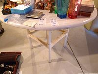 Photo showing top and partial legs of round white wooden table with various items on top.