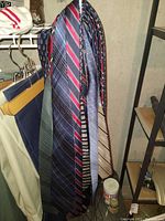 Photo showing assorted men's neck ties hanging, displaying various brands and patterns including striped and solid color ties.