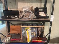 Shelving with tools and boxes including electric drill press stand, wrench set, bag of hardware, screwdriver bits, and Coleman Inflate-All.