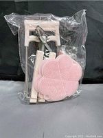 All five items sealed in plastic bag, showing contents of kitchen anti-scalding set in pink: two potholder mats, bowl clip, mini mitt, plate gripper.